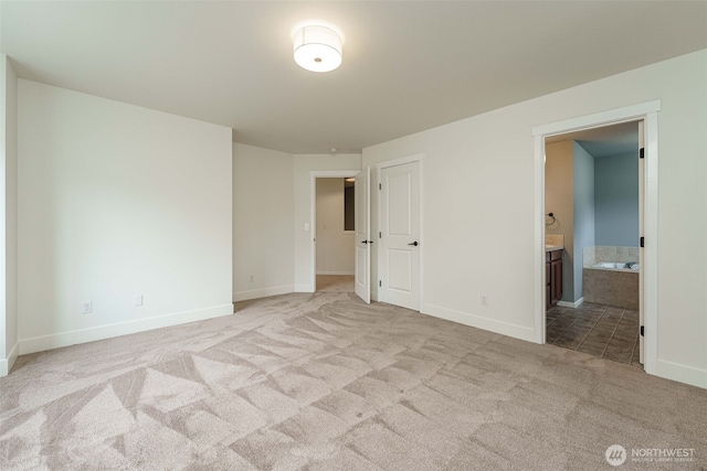 unfurnished bedroom featuring connected bathroom, baseboards, and carpet floors