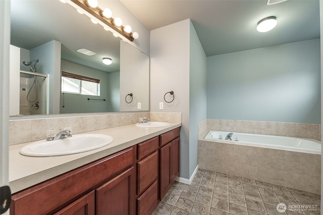 bathroom featuring a shower stall, a garden tub, double vanity, and a sink