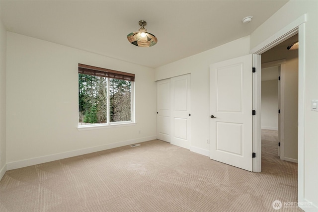 unfurnished bedroom with visible vents, light colored carpet, baseboards, and a closet