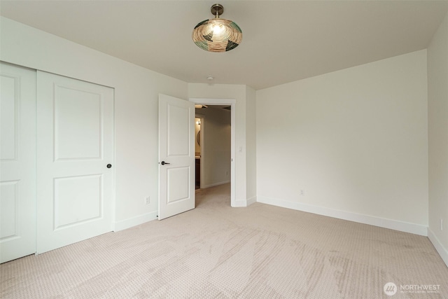 unfurnished bedroom featuring a closet, baseboards, and light colored carpet