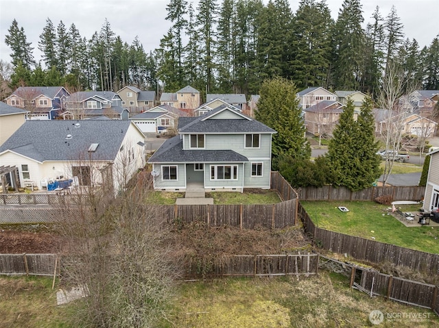 exterior space with a yard, a residential view, a fenced backyard, and a shingled roof