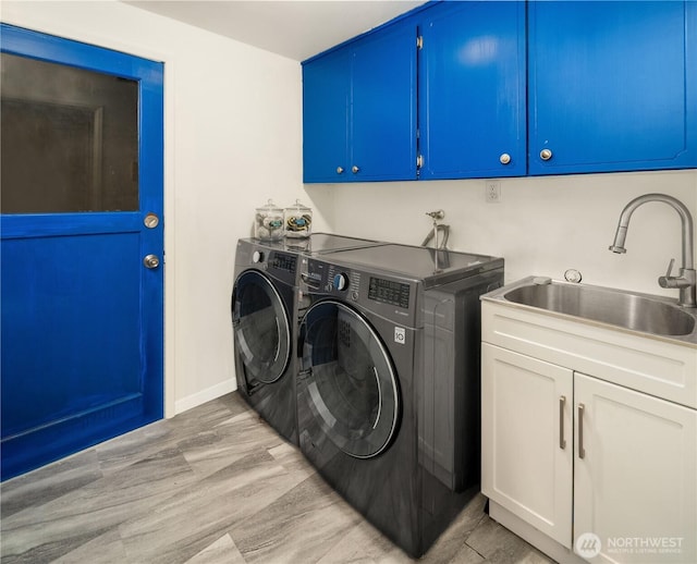 clothes washing area featuring cabinet space, washer and dryer, light wood-style floors, and a sink