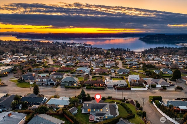 aerial view at dusk featuring a residential view and a water view