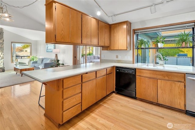 kitchen with light countertops, black dishwasher, light wood finished floors, and a sink