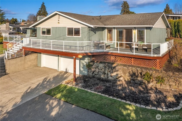 rear view of property featuring a garage and driveway