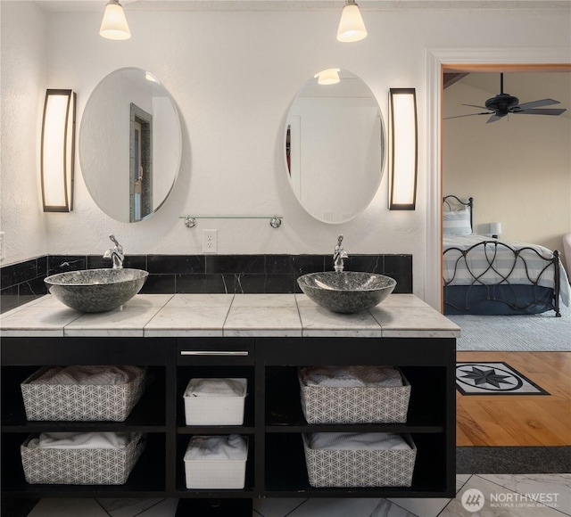 bathroom featuring ceiling fan, double vanity, wood finished floors, and a sink