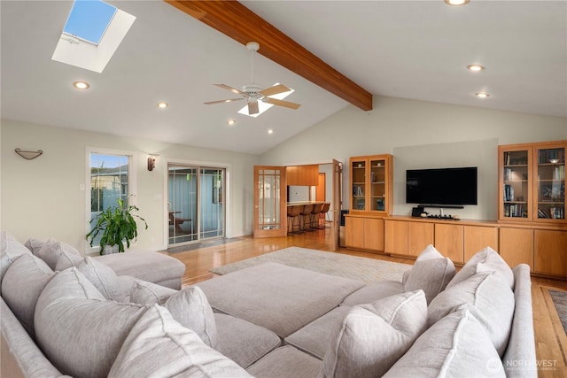 living area with vaulted ceiling with skylight, light wood-style flooring, recessed lighting, and ceiling fan