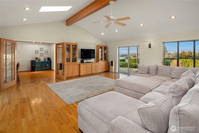 living area with a wealth of natural light, vaulted ceiling with skylight, light wood-style floors, and ceiling fan