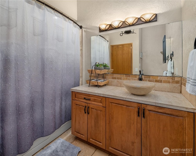 full bathroom featuring curtained shower, vanity, and a textured wall