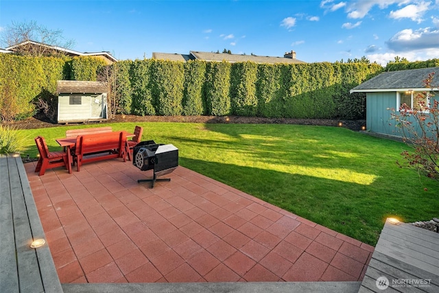 view of patio / terrace with an outbuilding, a fenced backyard, and a shed