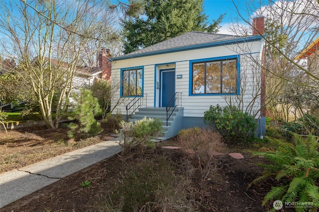 bungalow-style home with roof with shingles and a chimney