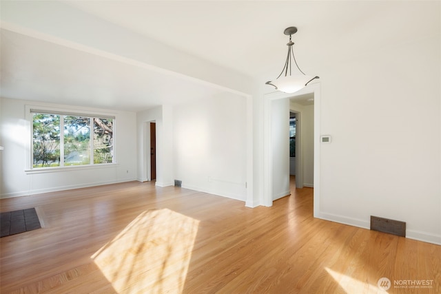 spare room featuring visible vents, light wood-type flooring, and baseboards