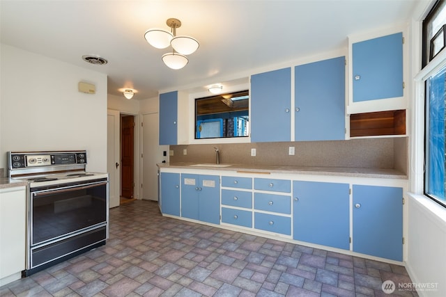 kitchen featuring visible vents, blue cabinetry, light countertops, and electric range oven