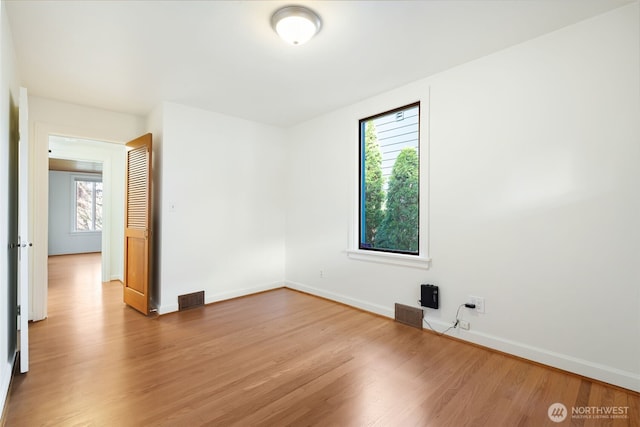 empty room featuring visible vents, baseboards, and wood finished floors