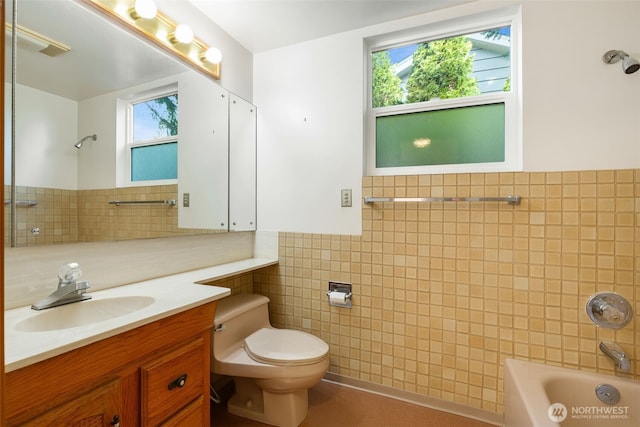 bathroom with toilet, tub / shower combination, tile walls, and vanity