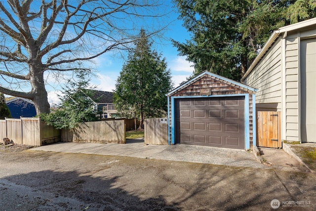 detached garage featuring fence and driveway