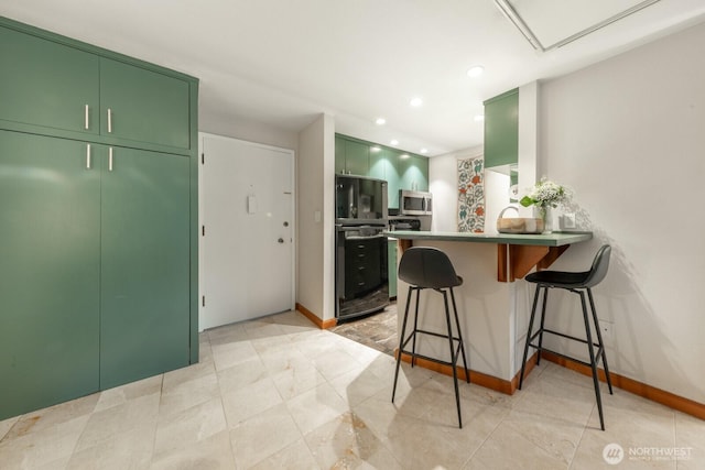 kitchen featuring stainless steel microwave, a kitchen bar, a peninsula, refrigerator, and green cabinetry