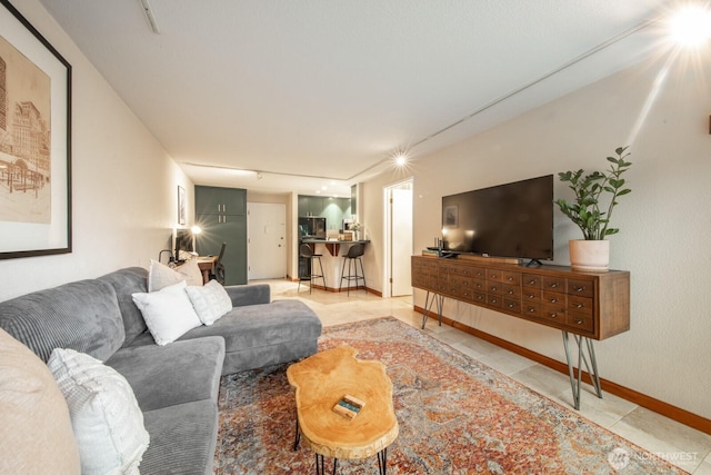 living room with baseboards, light tile patterned flooring, and track lighting