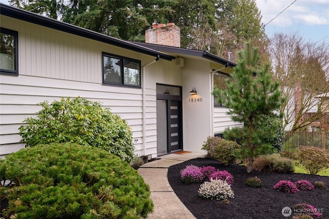 property entrance with a chimney and fence