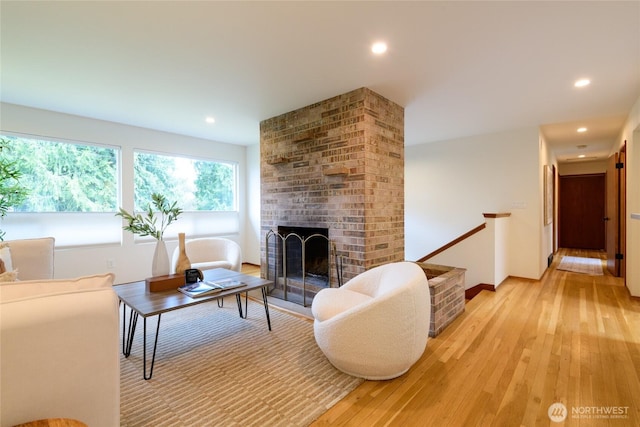 living room featuring recessed lighting, a fireplace, baseboards, and light wood-style floors