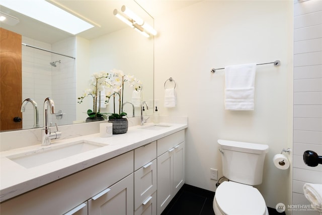 bathroom featuring double vanity, toilet, walk in shower, and a sink