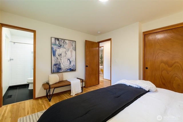 bedroom featuring a closet, baseboards, ensuite bath, and wood finished floors