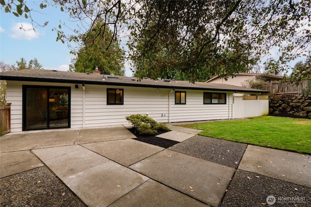 rear view of house with a patio area, a yard, and fence