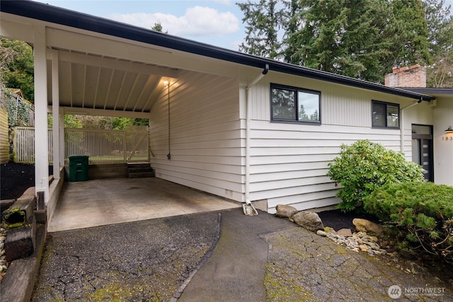 exterior space with an attached carport, driveway, and a chimney