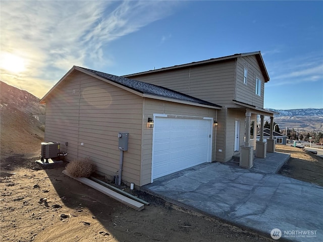 view of side of property with a garage, central AC, concrete driveway, and a mountain view