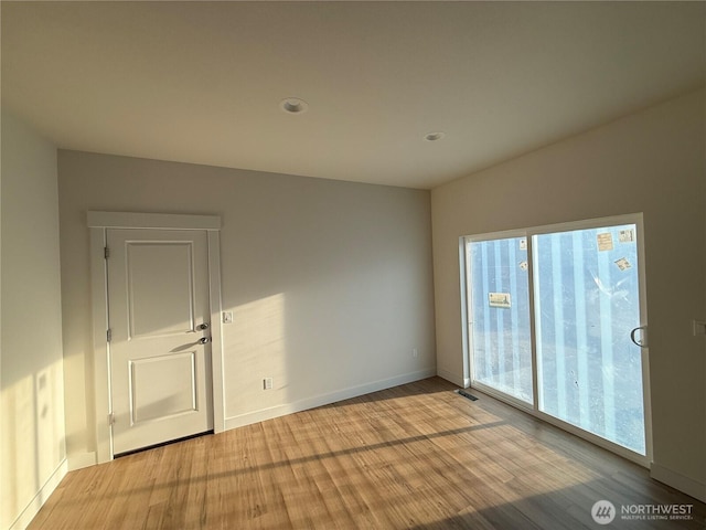 empty room featuring visible vents, light wood-type flooring, and baseboards