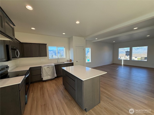 kitchen with a sink, stainless steel appliances, light wood-style flooring, and light countertops