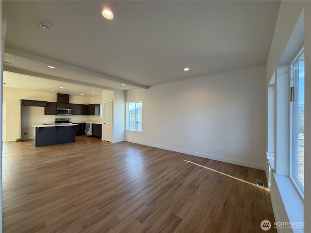 unfurnished living room with dark wood finished floors, recessed lighting, and baseboards