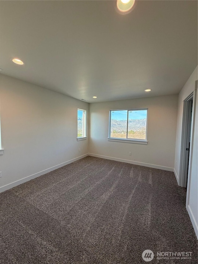 spare room with recessed lighting, baseboards, and dark carpet