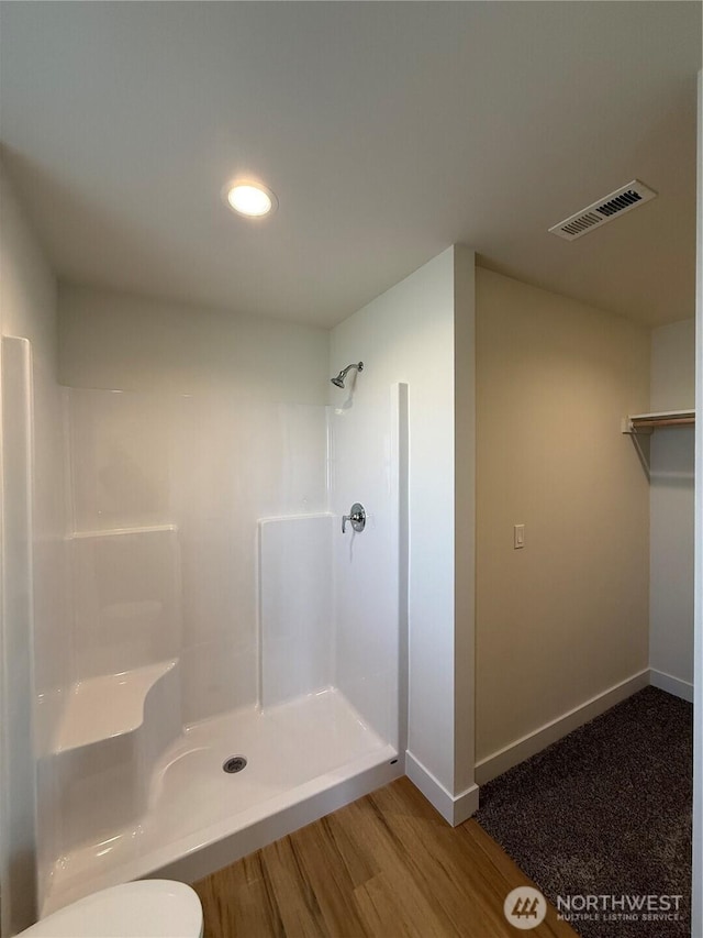 bathroom with visible vents, toilet, wood finished floors, a shower, and baseboards