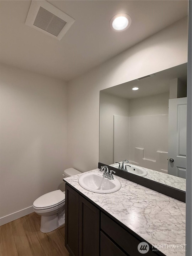 bathroom with vanity, wood finished floors, visible vents, baseboards, and toilet