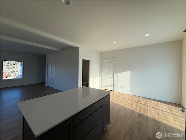 interior space with recessed lighting, baseboards, a kitchen island, and dark wood-style flooring