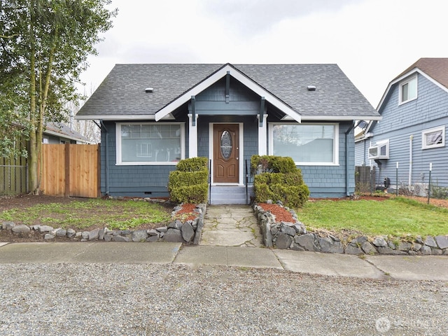 bungalow featuring a shingled roof, a front lawn, fence, and crawl space