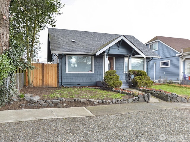 view of front of property with crawl space, a shingled roof, and fence