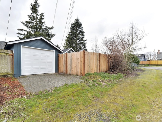 garage with gravel driveway and fence