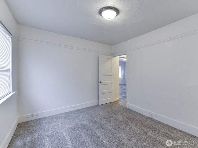 spare room featuring carpet flooring, baseboards, and a textured ceiling