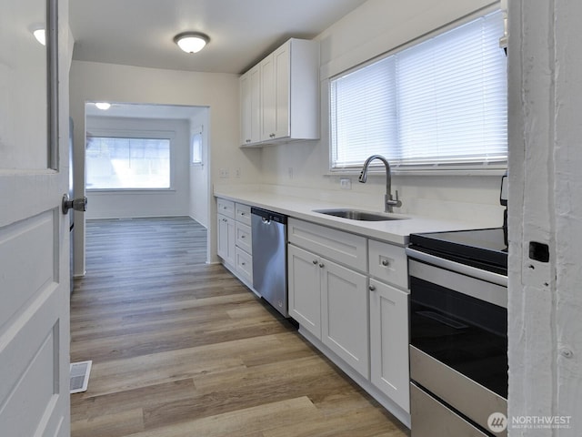 kitchen with visible vents, light wood-style flooring, a sink, stainless steel appliances, and white cabinetry