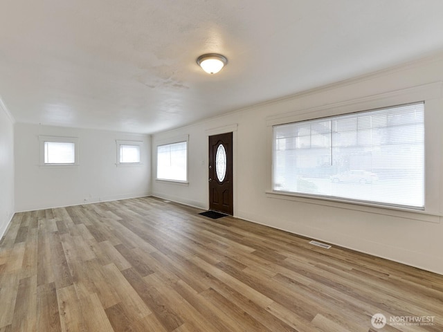 foyer entrance featuring visible vents, baseboards, and light wood-style flooring