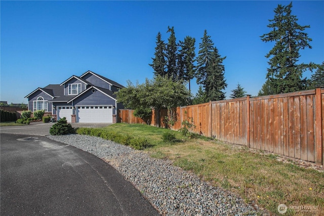 view of front of house with driveway, an attached garage, a front yard, and fence