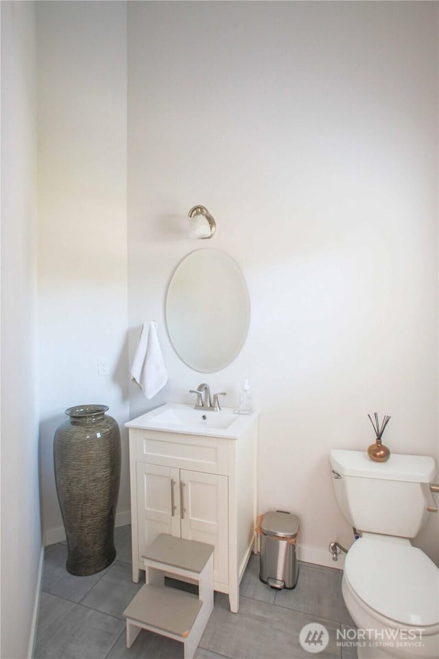 half bath featuring tile patterned flooring, toilet, vanity, and baseboards