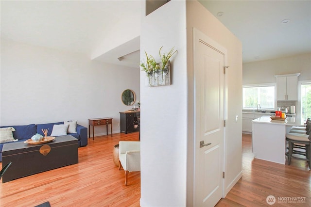 hallway featuring light wood-style floors and a sink