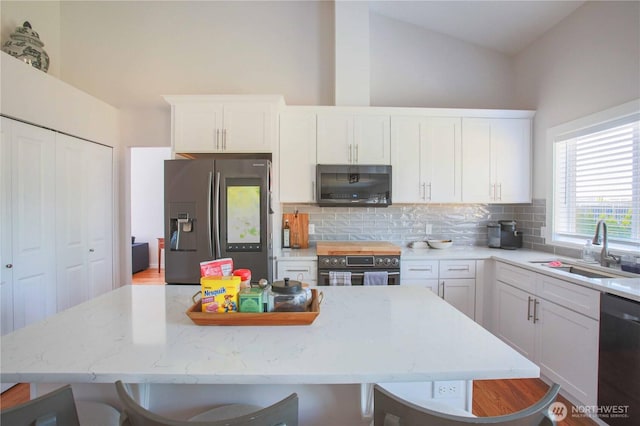 kitchen featuring a kitchen breakfast bar, tasteful backsplash, appliances with stainless steel finishes, and a sink