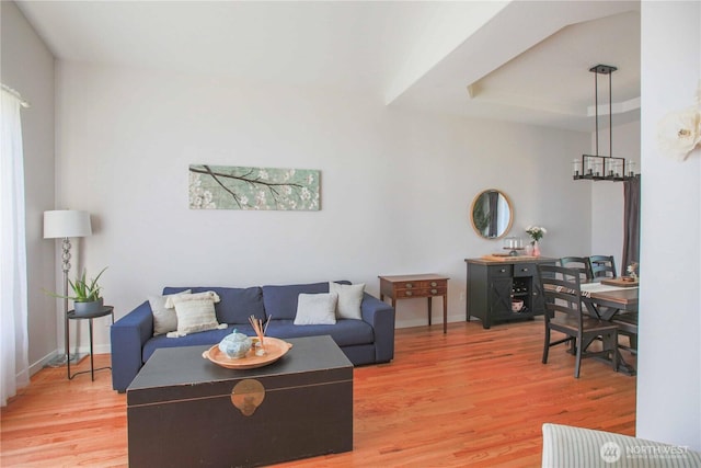 living area with baseboards, light wood-style floors, and a chandelier