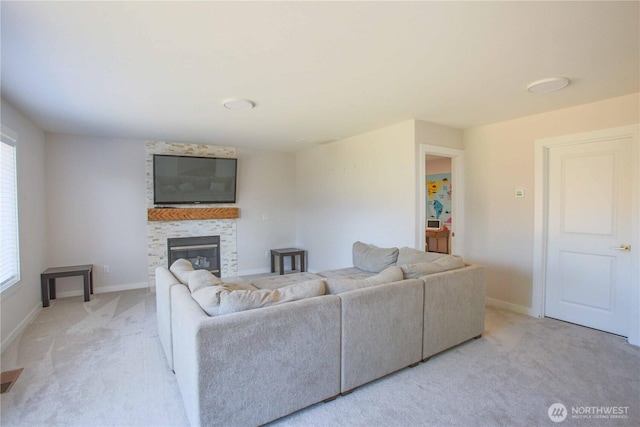 living area with light carpet, a glass covered fireplace, and baseboards