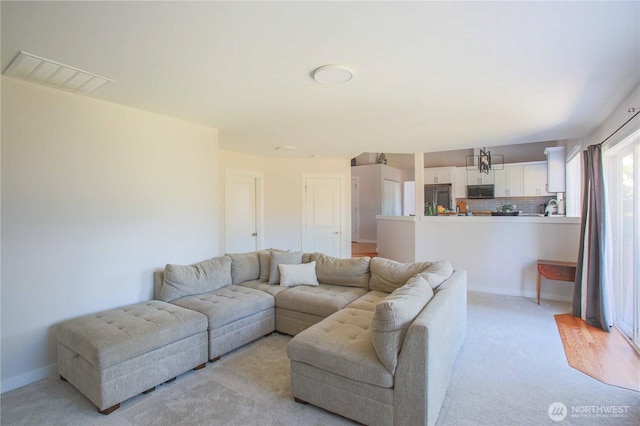 living room featuring baseboards, visible vents, and light carpet