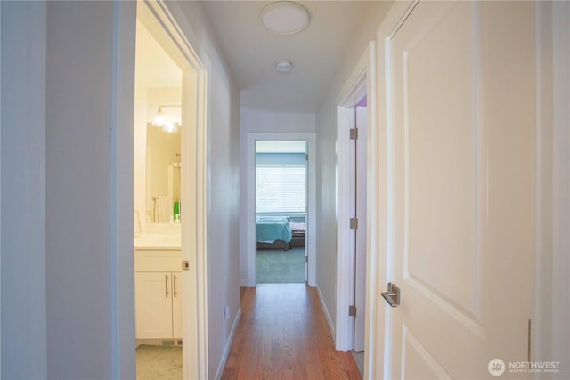 hall with baseboards and light wood-style floors